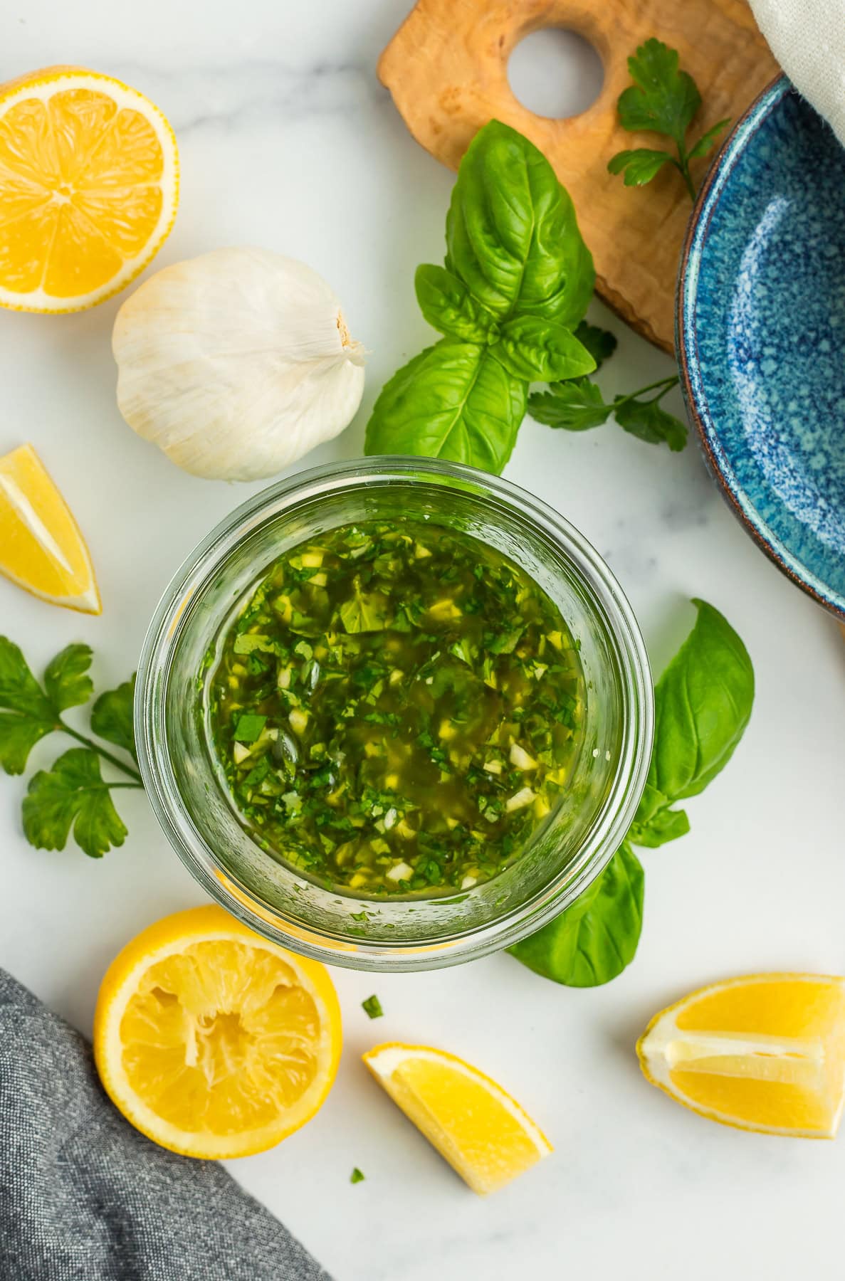 a mixed up sauce in a glass jar with fresh green herbs.