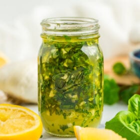 a side profile photo of a small glass jar of garlic and lemon chicken marinade.