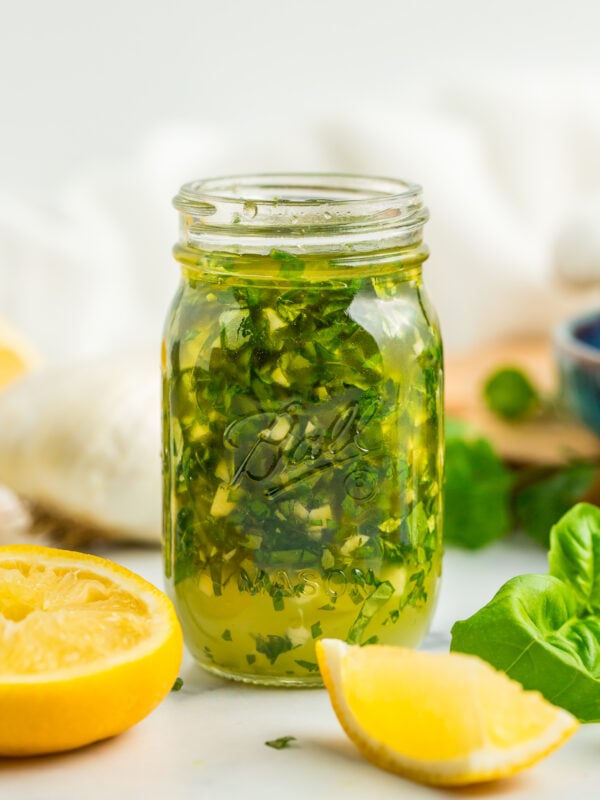 a side profile photo of a small glass jar of garlic and lemon chicken marinade.
