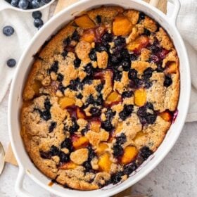 peach and blueberry cobbler in a white baking dish.