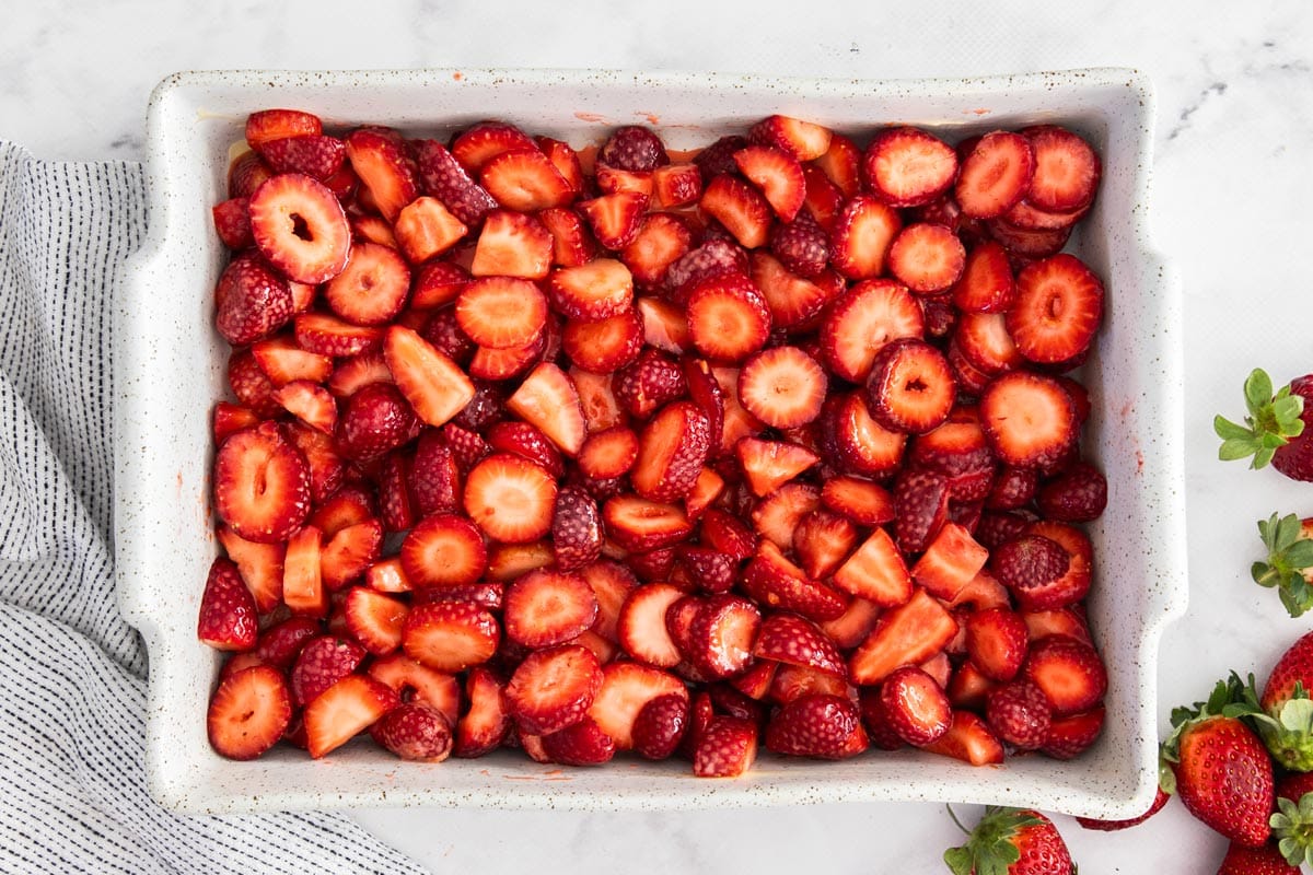 sliced strawberries in a white baking dish.