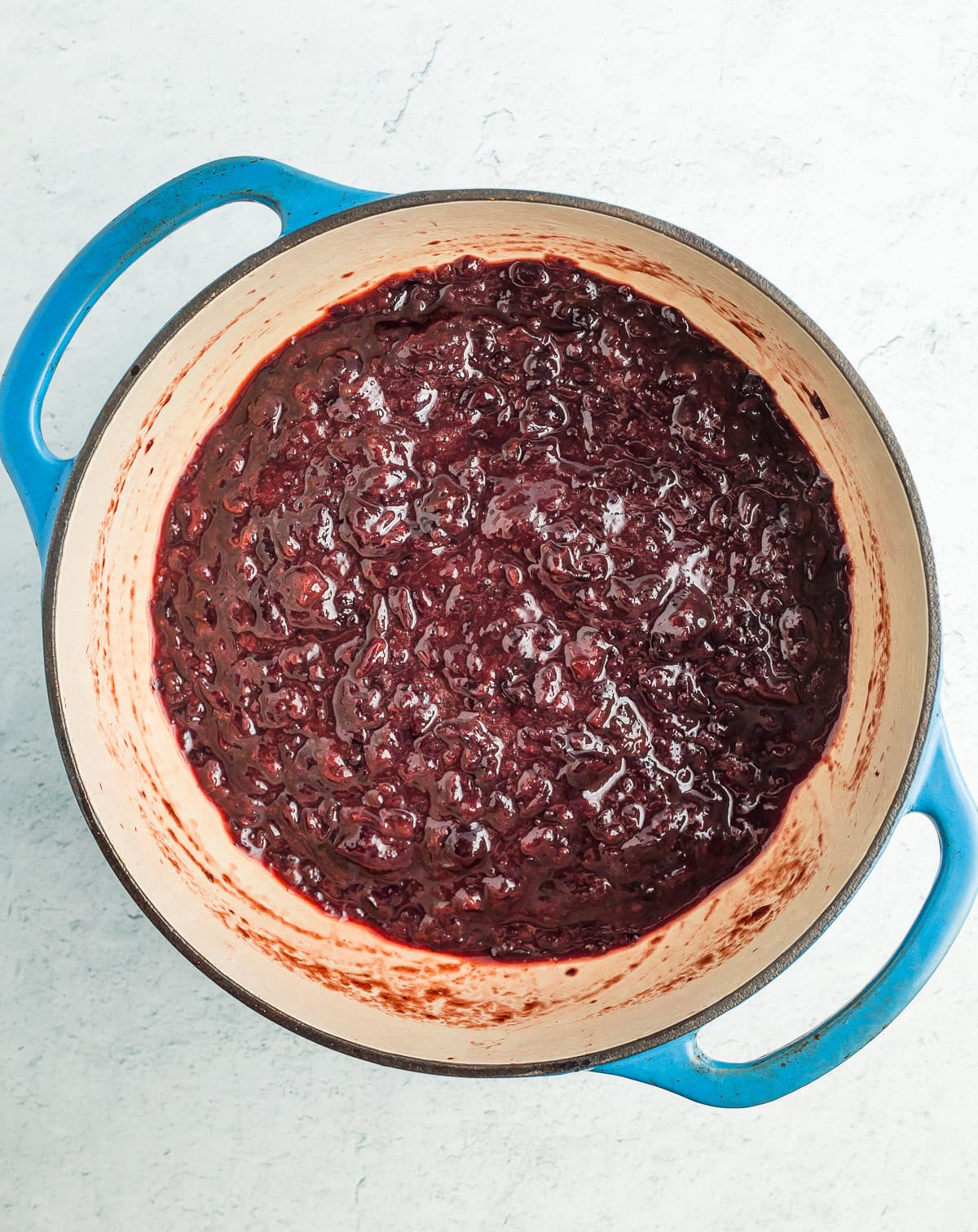 a blue dutch oven with chopped cherries in it.