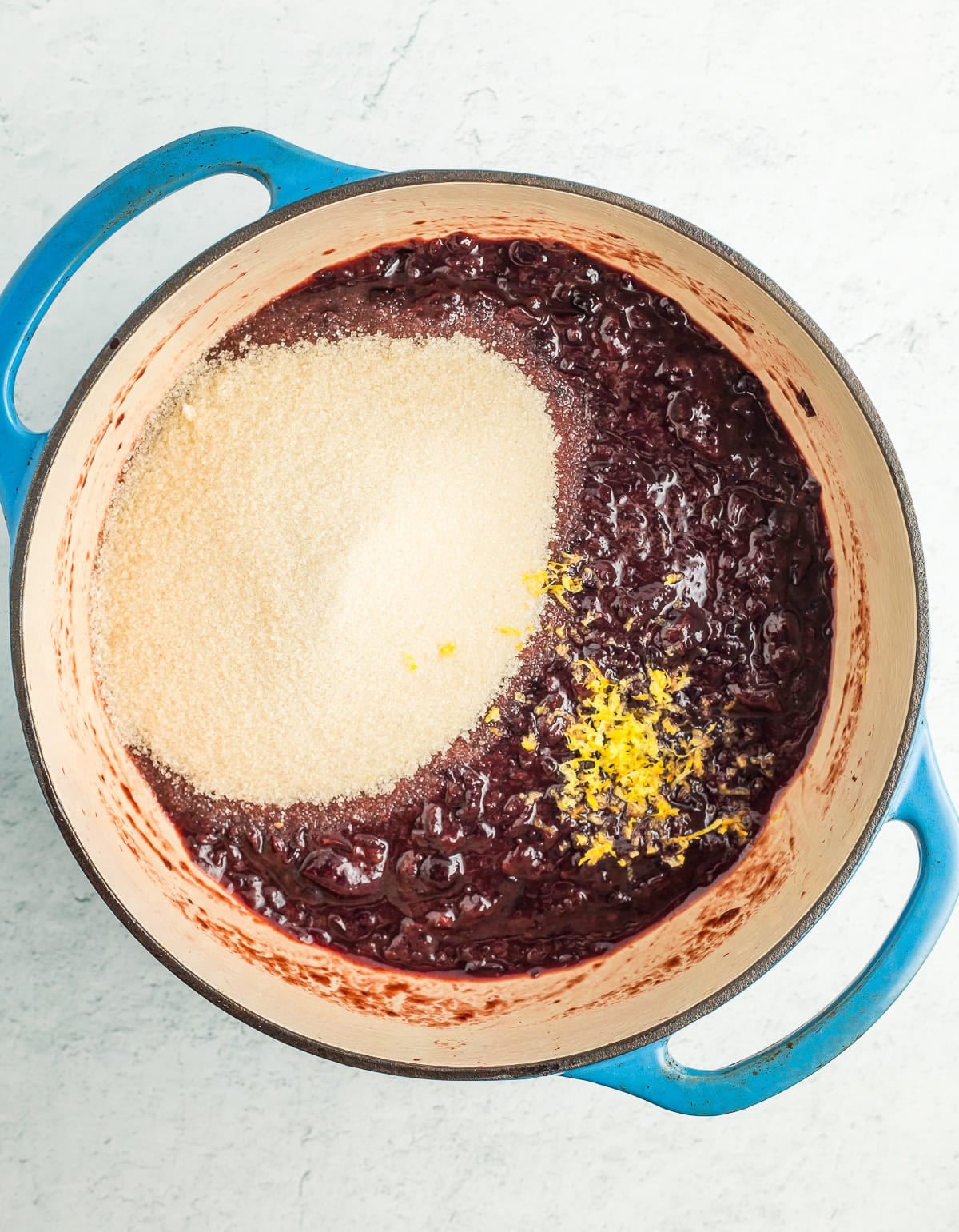 chopped cherries, sugar, and lemon zest in a blue dutch oven.
