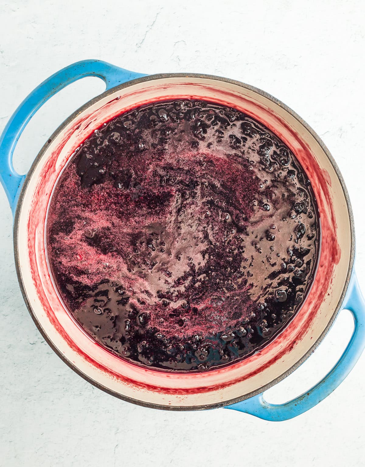 cherry sauce being cooked in a blue dutch oven.