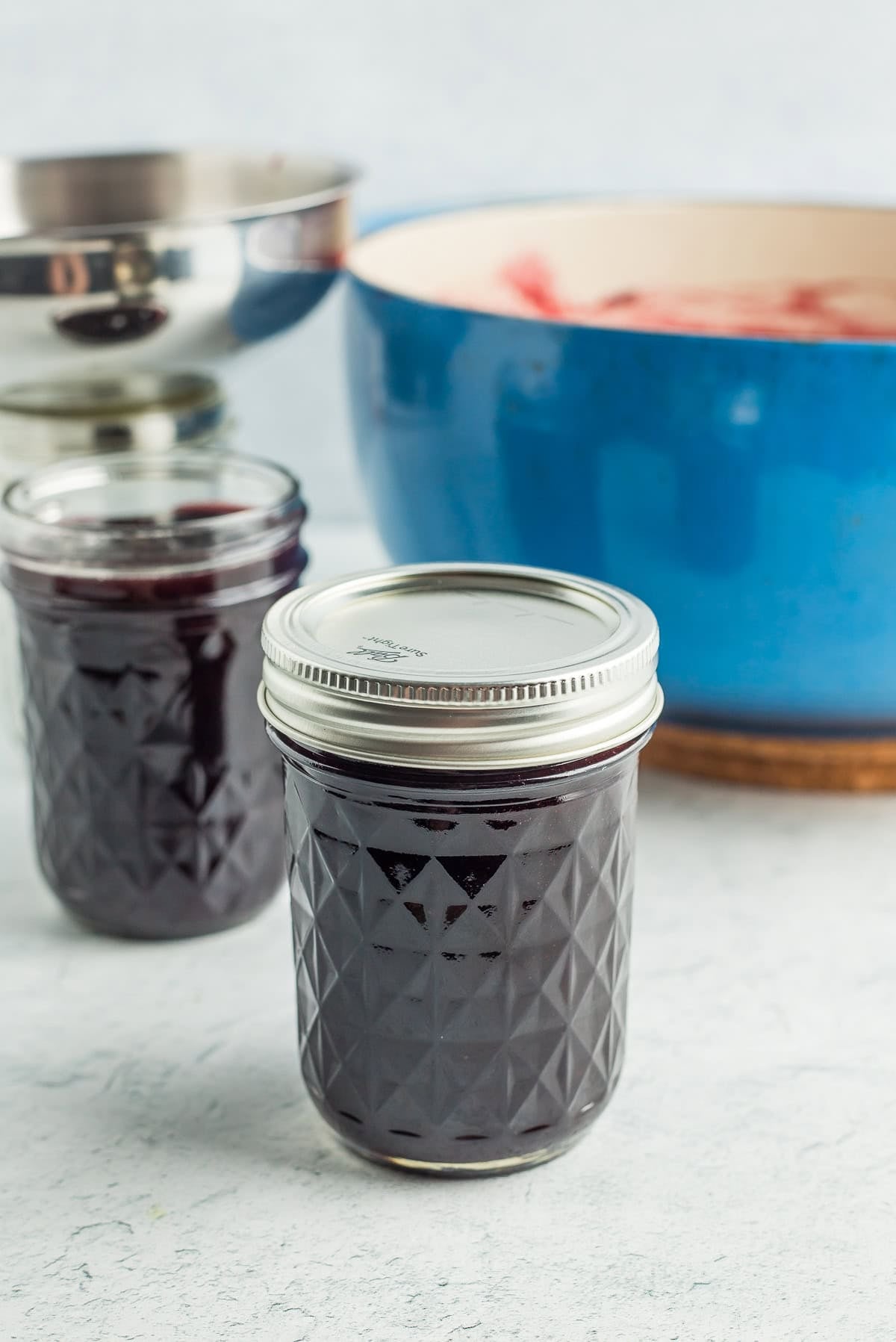 a canning jar with a lid and a ring on it in front of a blue Dutch oven.