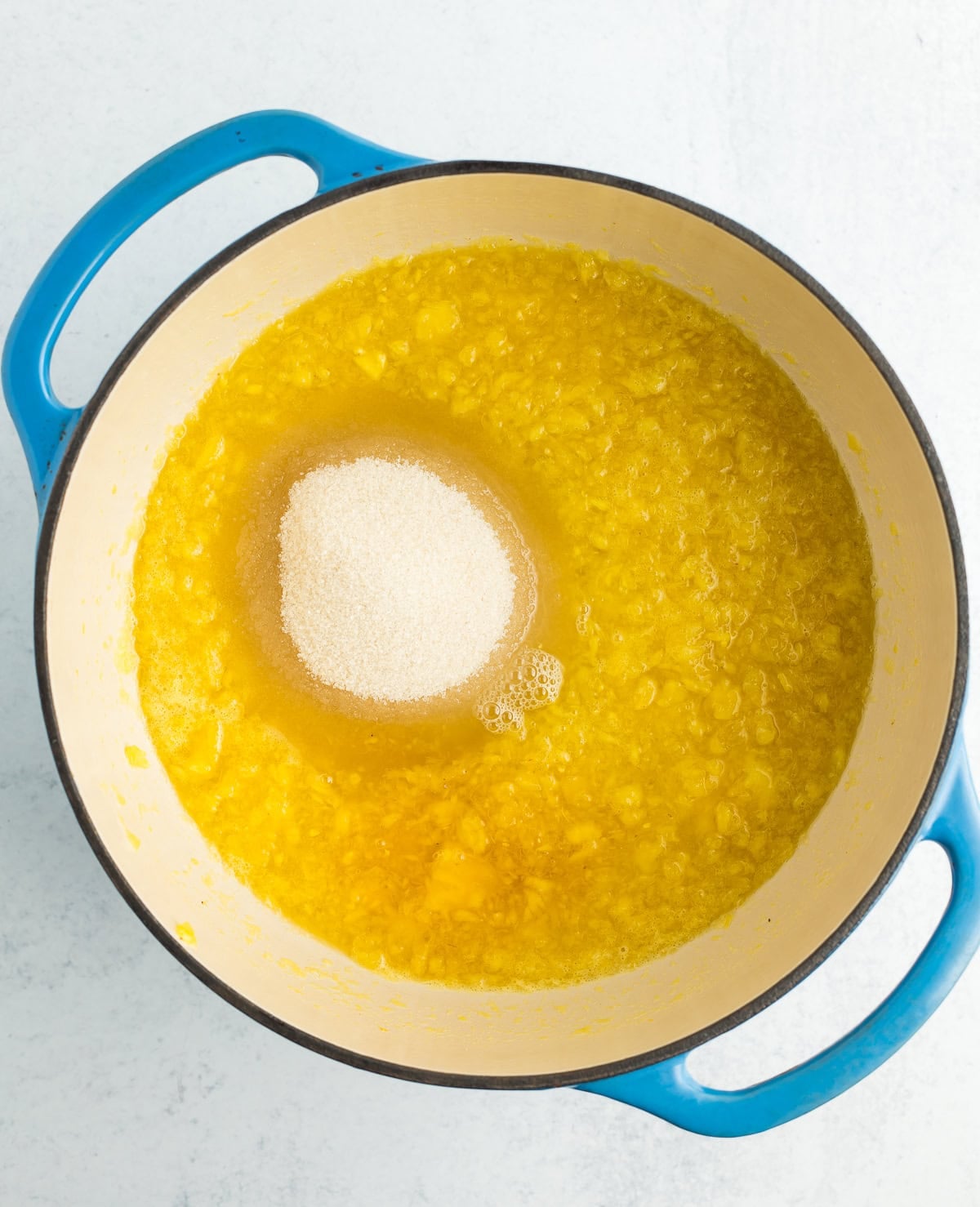 fruit sauce and sugar in a blue Dutch oven.