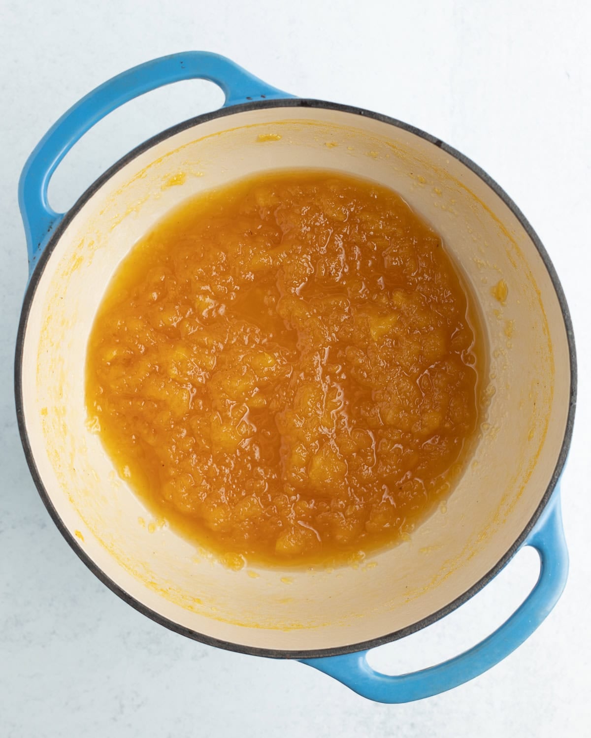 a dark pineapple sauce in a blue Dutch oven.