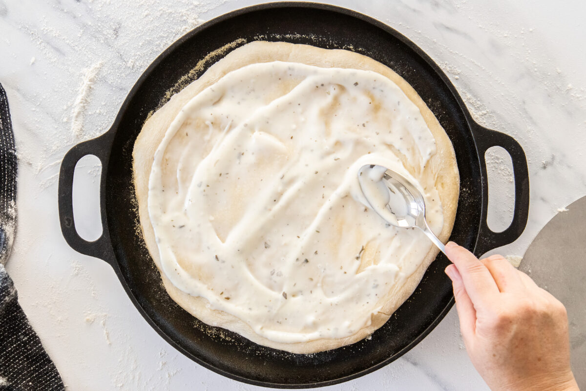 ranch dressing being spread on unbaked dough with a spoon.