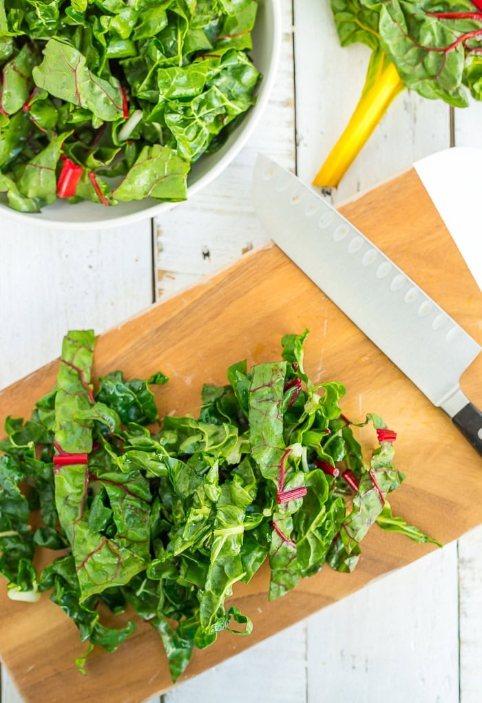 chopped greens on a cutting board with a knife.