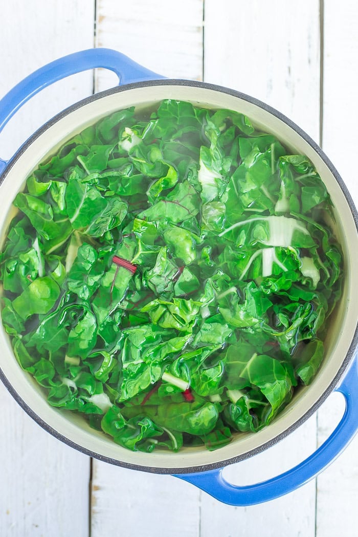 chopped greens in a blue Dutch oven.