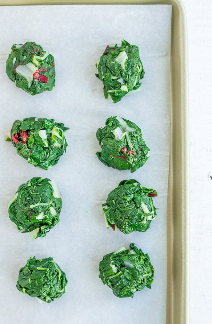 small bundles of cooked greens on a baking sheet.