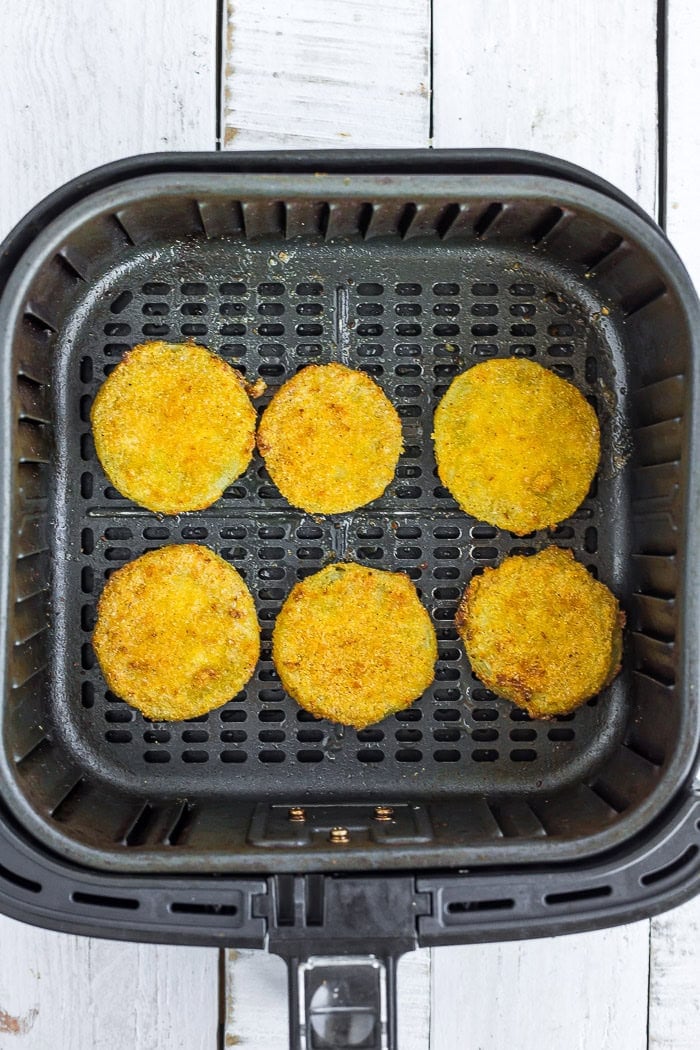 slices of battered fried tomatoes in an air fryer.