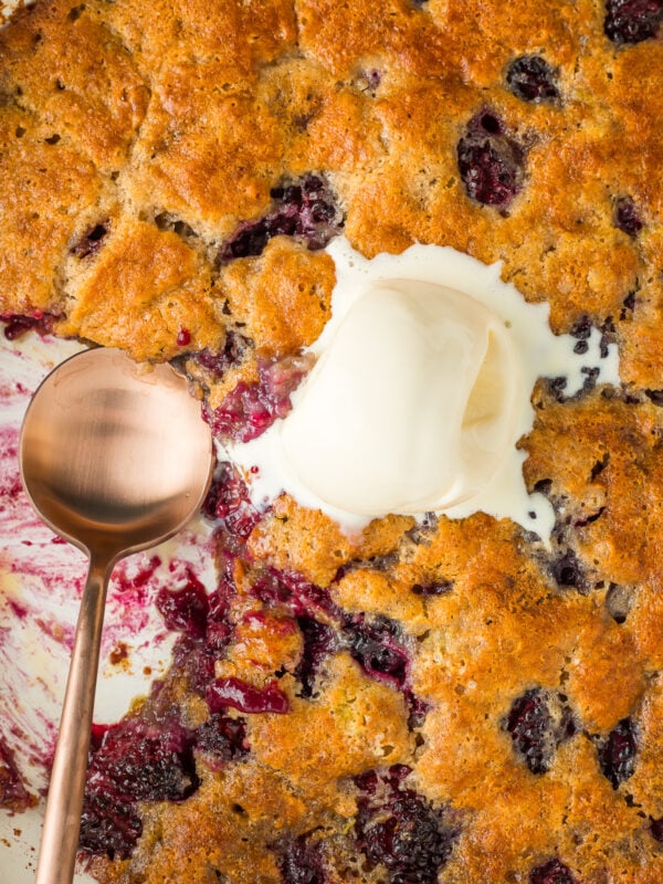 a blackberry cobbler with a serving missing and a scoop of vanilla ice cream in the middle.