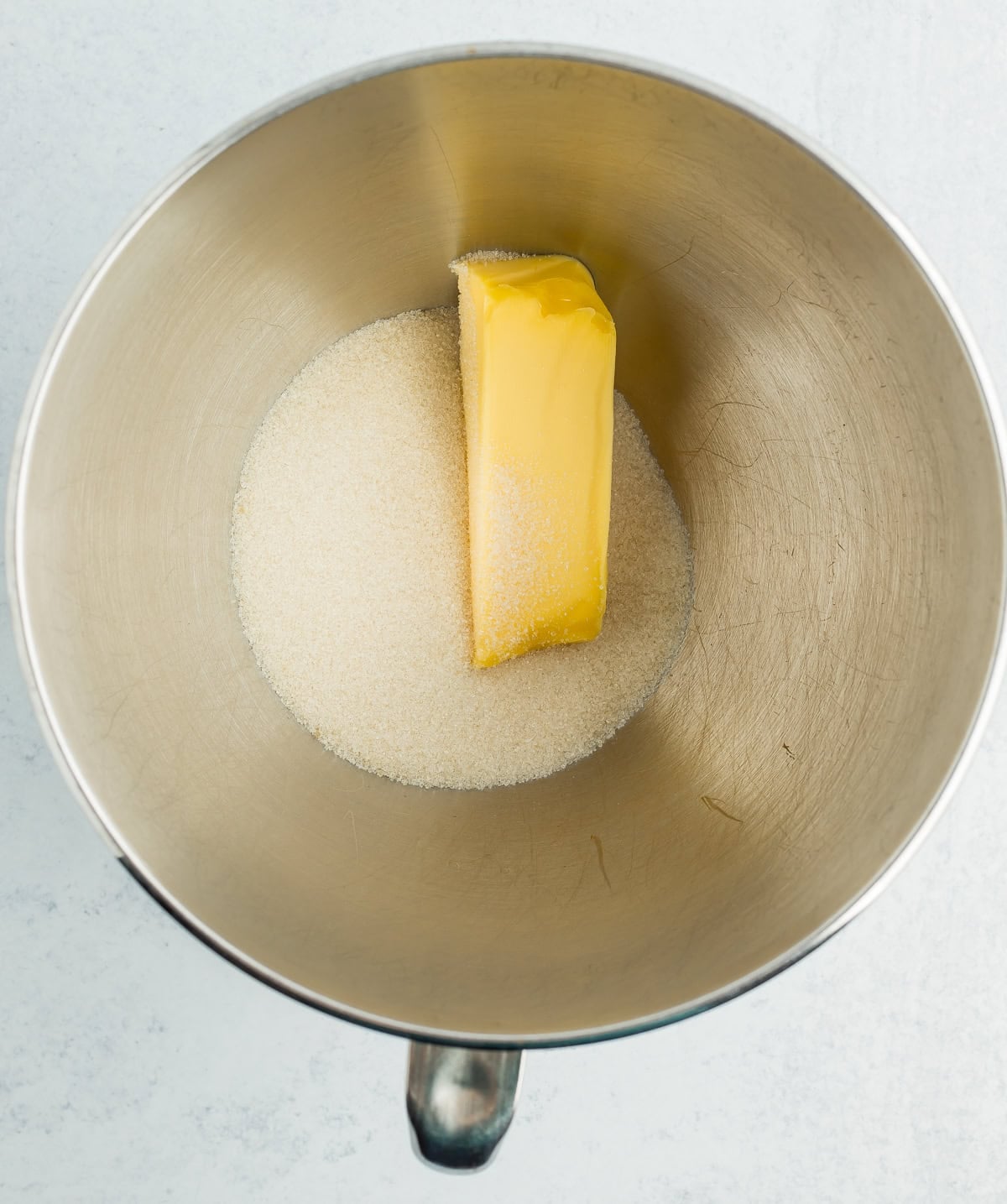 a stick of butter and white sugar in a stand mixing bowl.