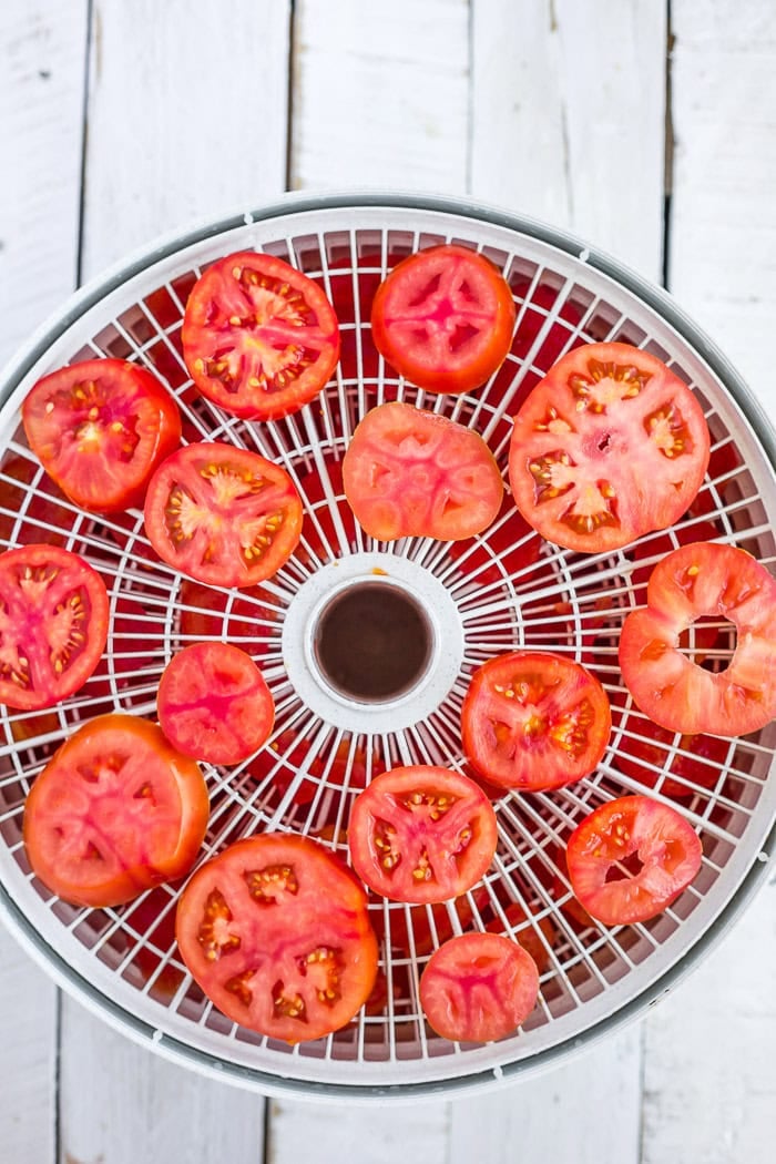 sliced tomatoes on a dehydrator tray.