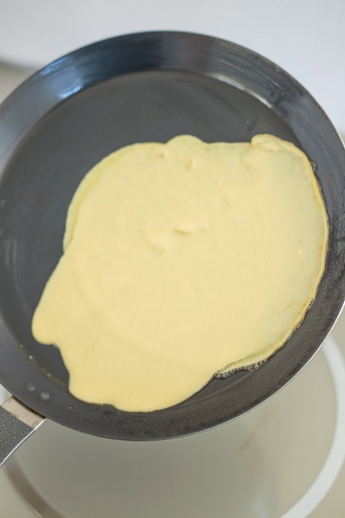 batter being swirled around a pan over a stove.