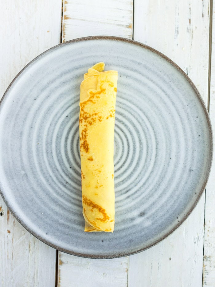 a rolled crepe on a grey plate.