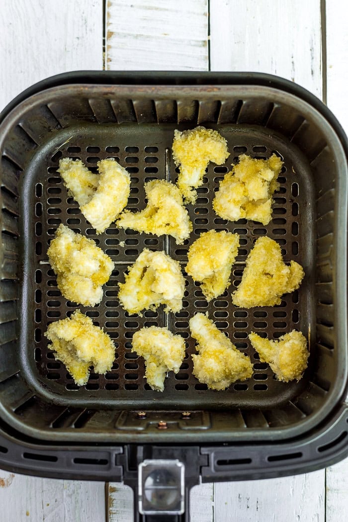 panko covered uncooked cauliflower in an air fryer.