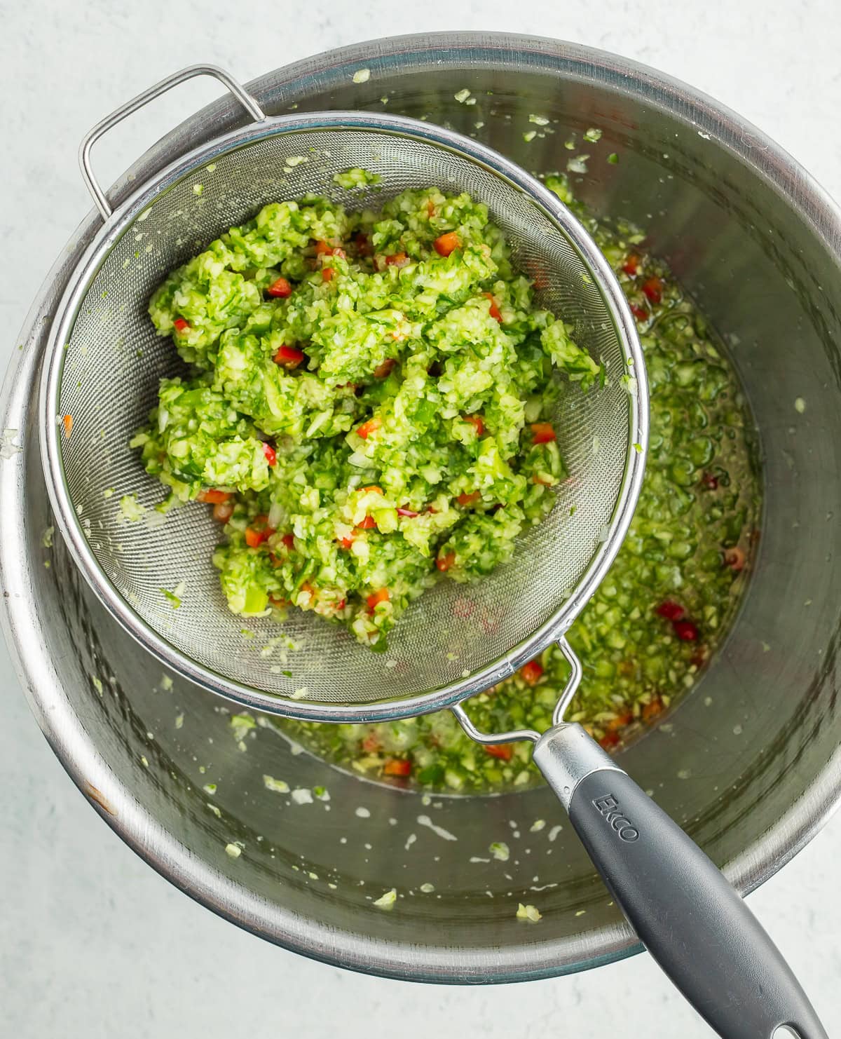 chopped vegetables in a metal strainer over a bowl.
