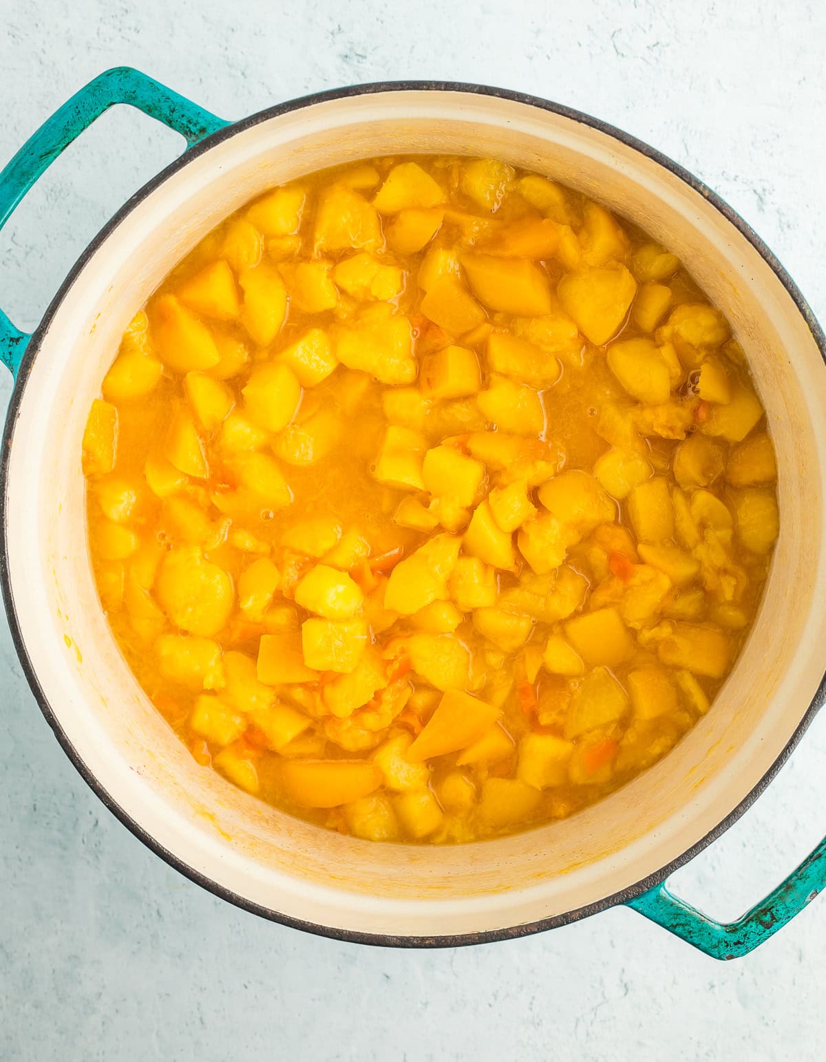 cooked fruit in a teal dutch oven.