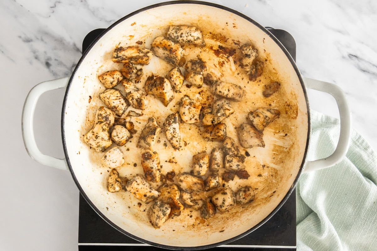 cooked cubes of chicken in a white skillet.