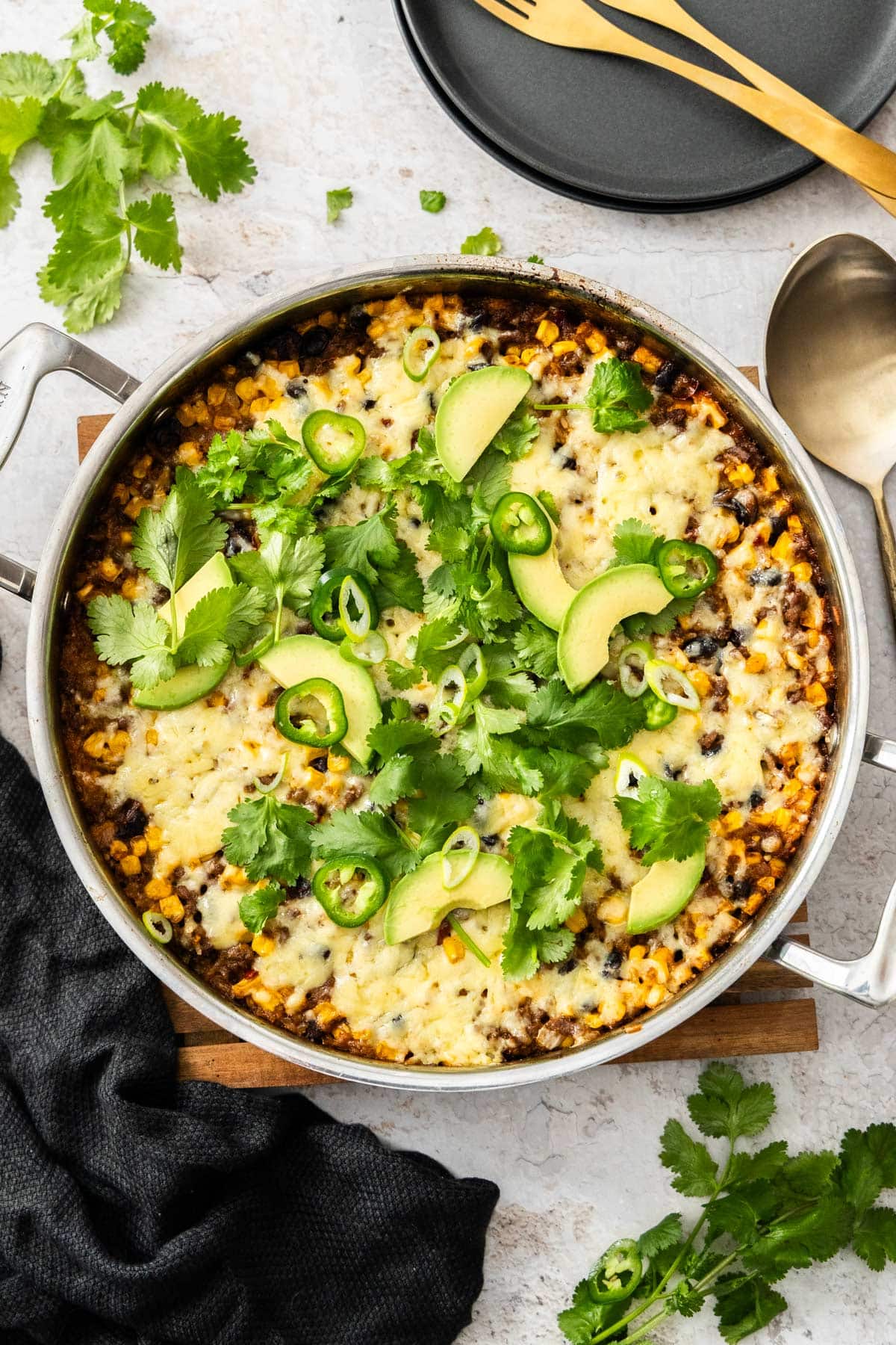 a taco-flavored beef and rice skillet topped with melted cheese, cilantro, green onions, and avocado.