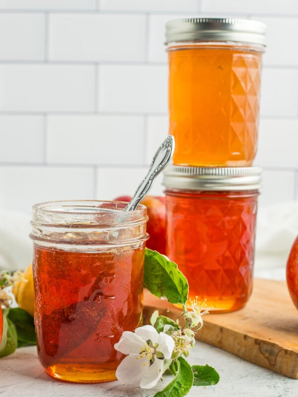 three jars of apple jelly with a small branch of apple tree blossoms.