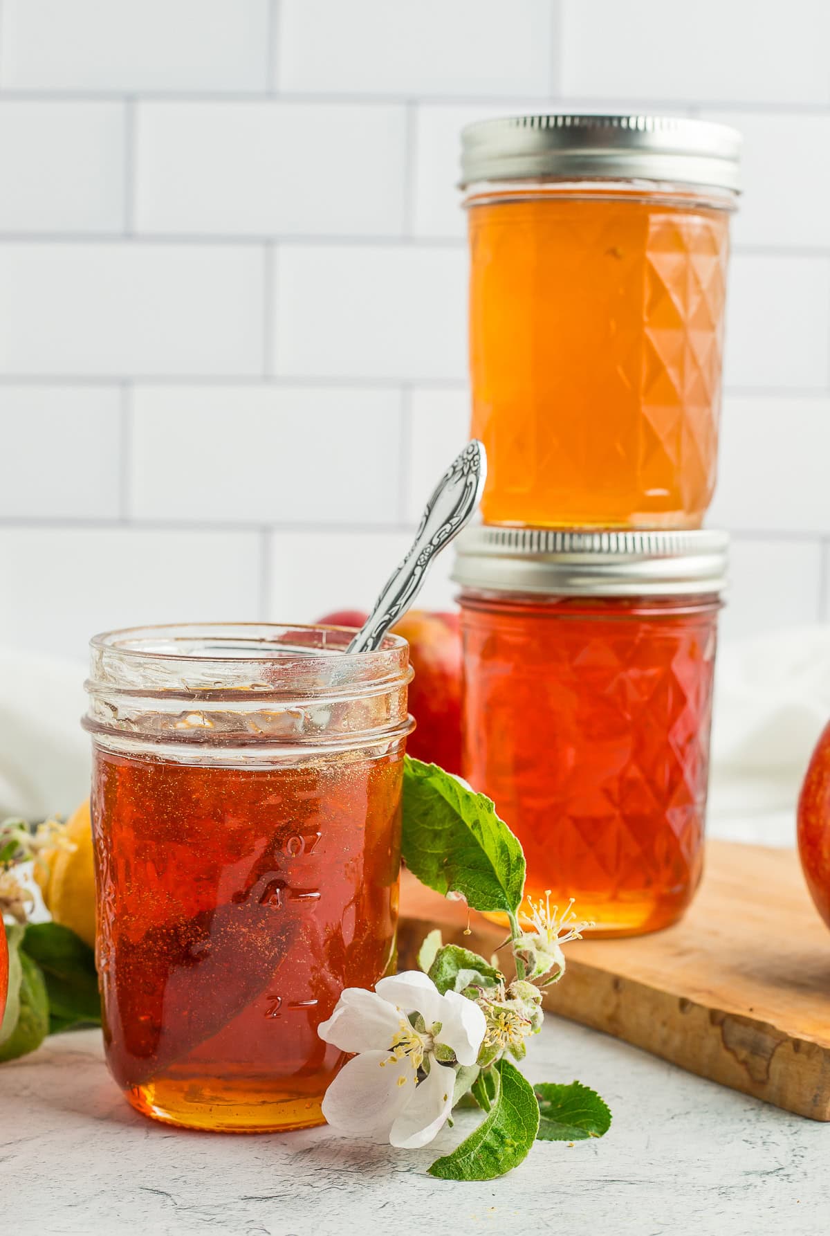 three jars of apple jelly with a small branch of apple tree blossoms.