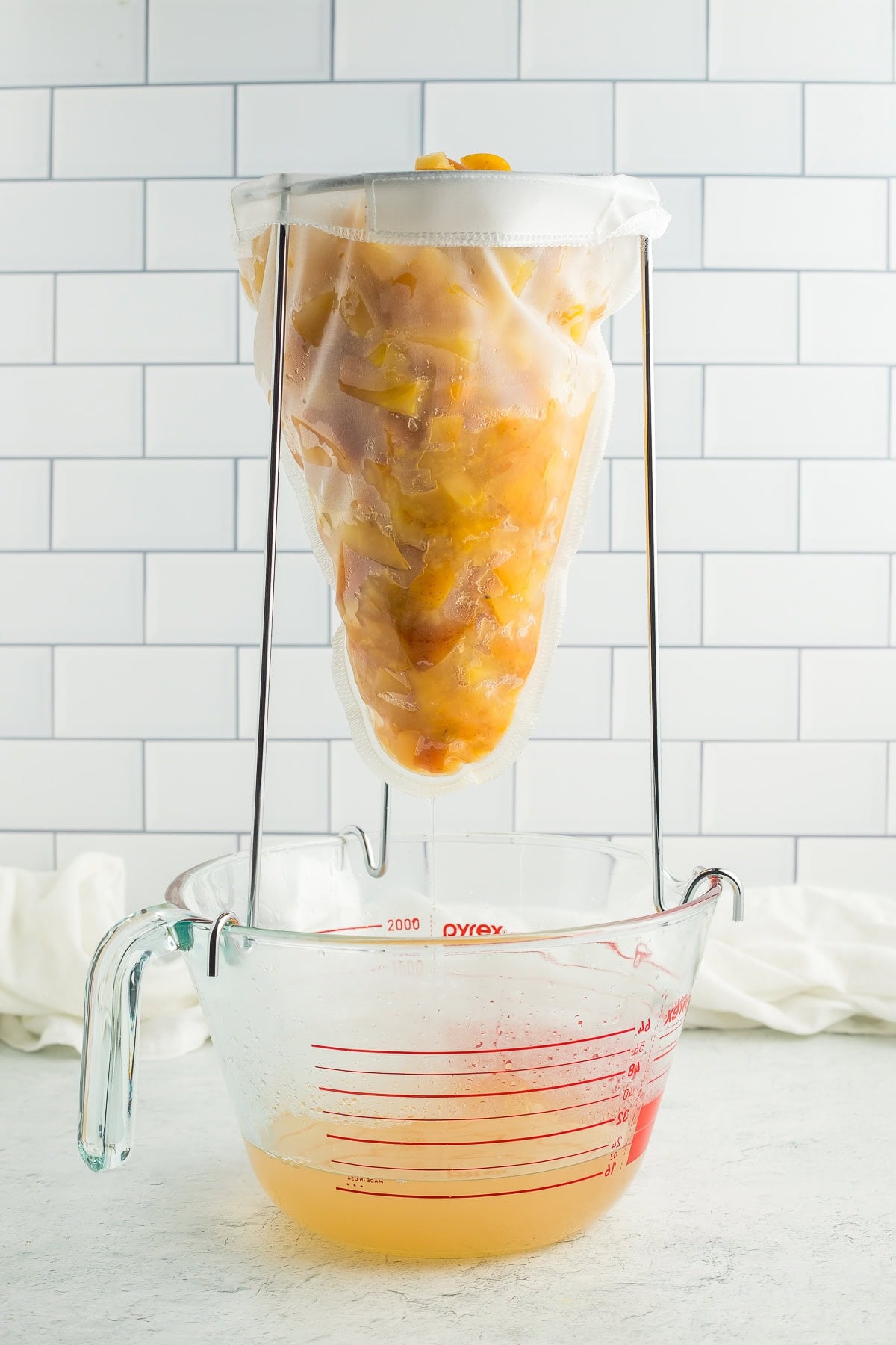 fruit in a jelly bag over a large glass measuring cup.