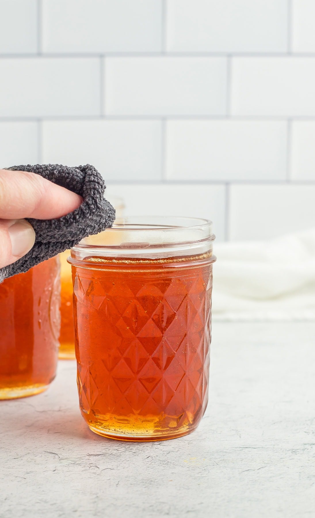 a hand wiping the rim of a canning jar.