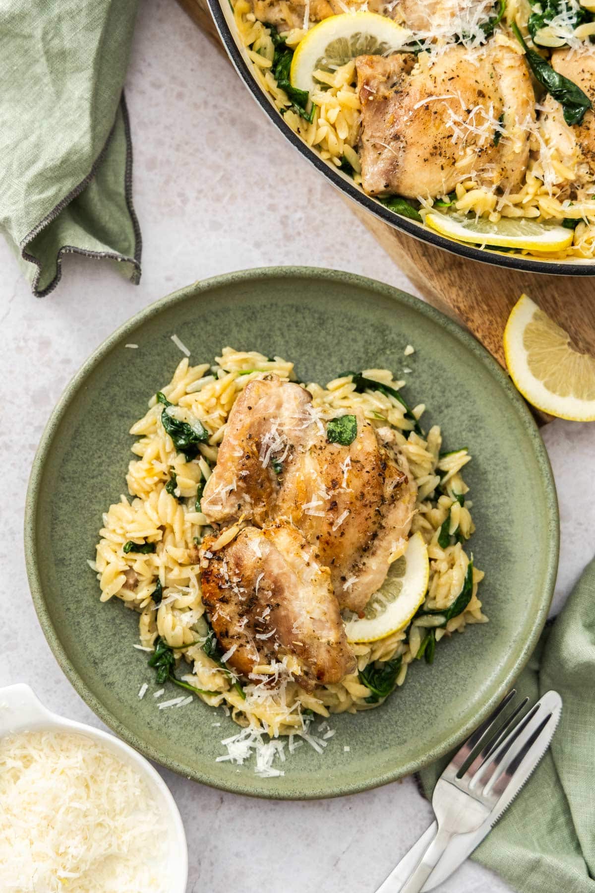 a green plate of orzo pasta with seared chicken