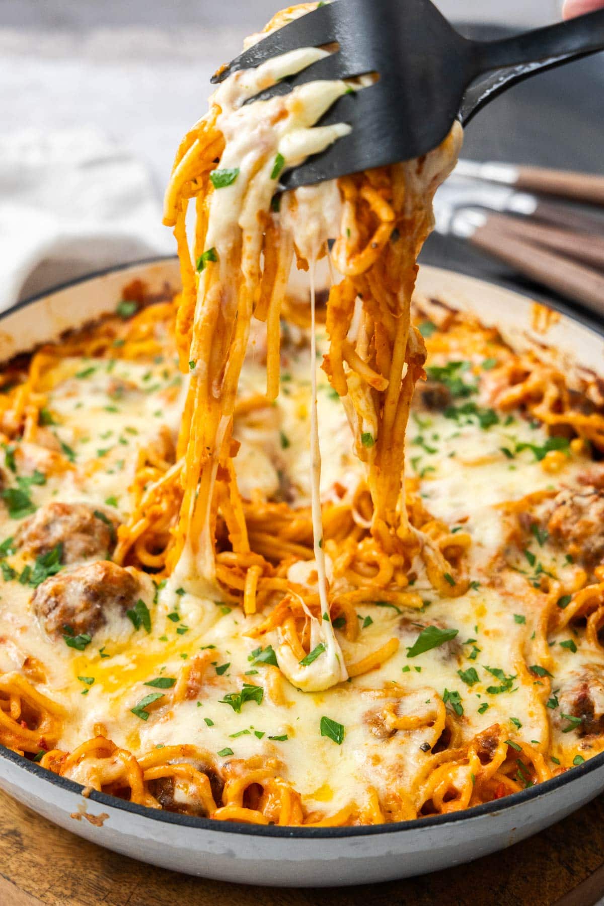 a fork and spoon with a serving of noodles hovering over a pot of casserole.