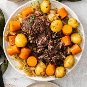 two white dishes of French onion pot roast with potato and cubed potatoes.