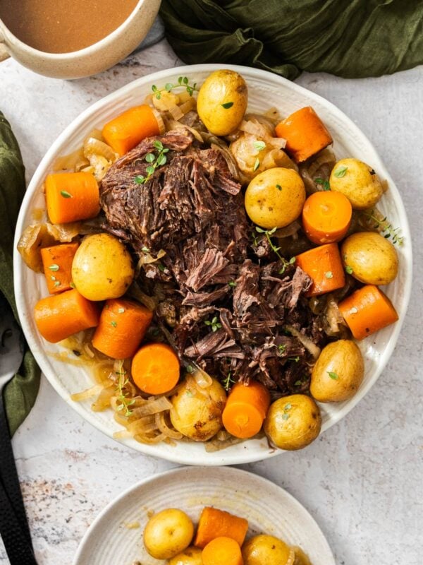 two white dishes of French onion pot roast with potato and cubed potatoes.