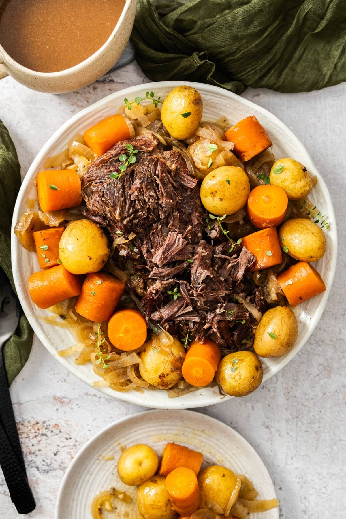 two white dishes of French onion pot roast with potato and cubed potatoes.